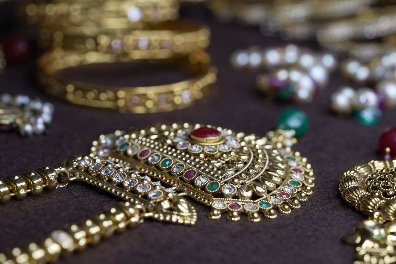 Close-up of traditional Indian gold jewelry with intricate design, featuring gems and pearls.
